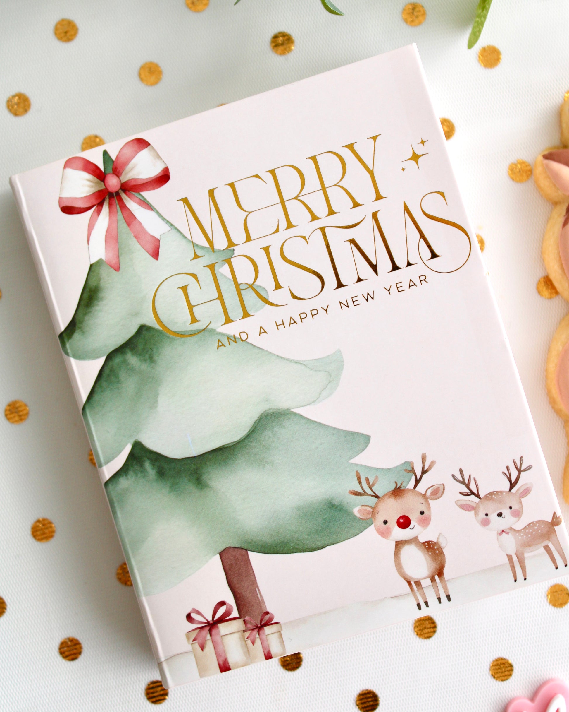 A festive Christmas cookie card box decorated with watercolour trees and reindeer, with “Merry Christmas and a Happy New Year” written on the front.
